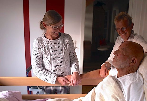 Ärztin an Patientenbett mit Anghöriger